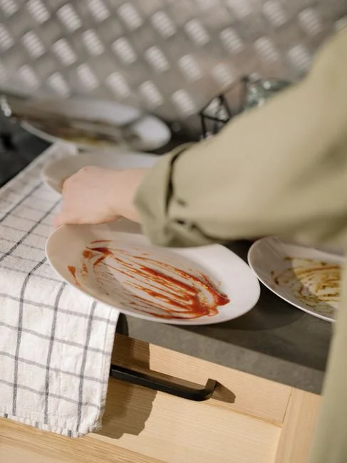 A hotel housekeeper neatly stacks fresh towels in a luxurious room setting.